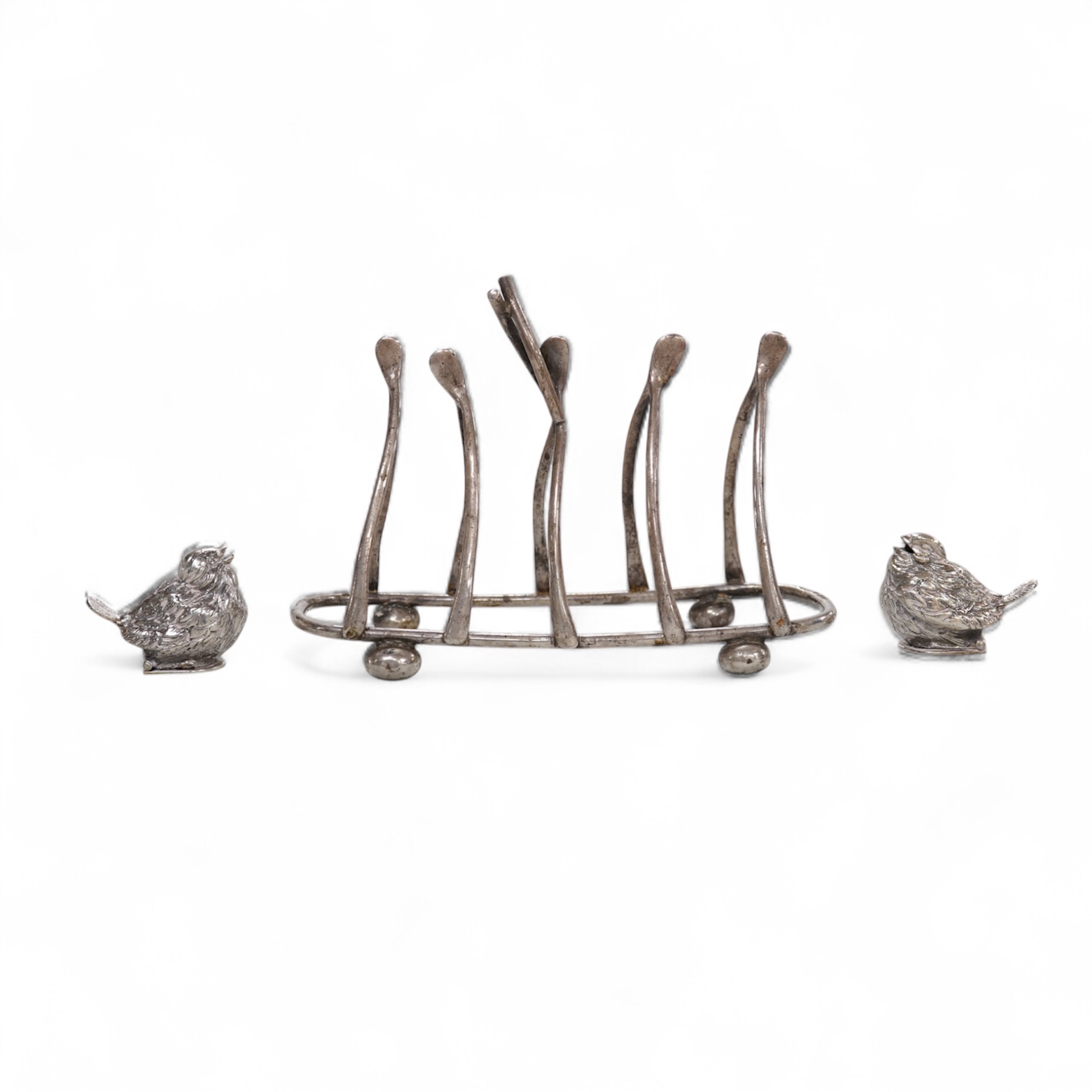 A George V novelty silver five bar 'wishbone' toast rack, Wilmot Manufacturing Co, Birmingham, 1919, length 13.7cm, together with a pair of Spanish white metal chick pepperettes.